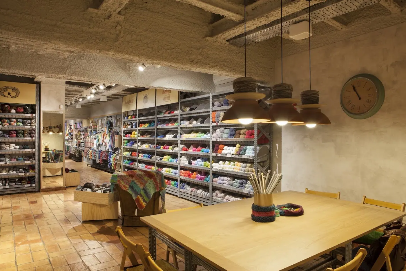 Sala de tienda con mesa de taller y muro de ovillos